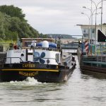 Eine beladene Péniche fährt in eine Schleuse des Canal du Nord ein