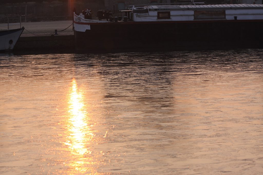 Die aufgehende Sonne spiegelt sich im Eis des Hafenbeckens